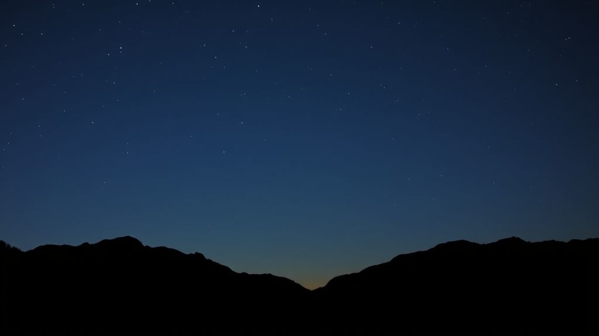 aurores boréales dans un ciel nocturne clair avec montagnes en silhouette